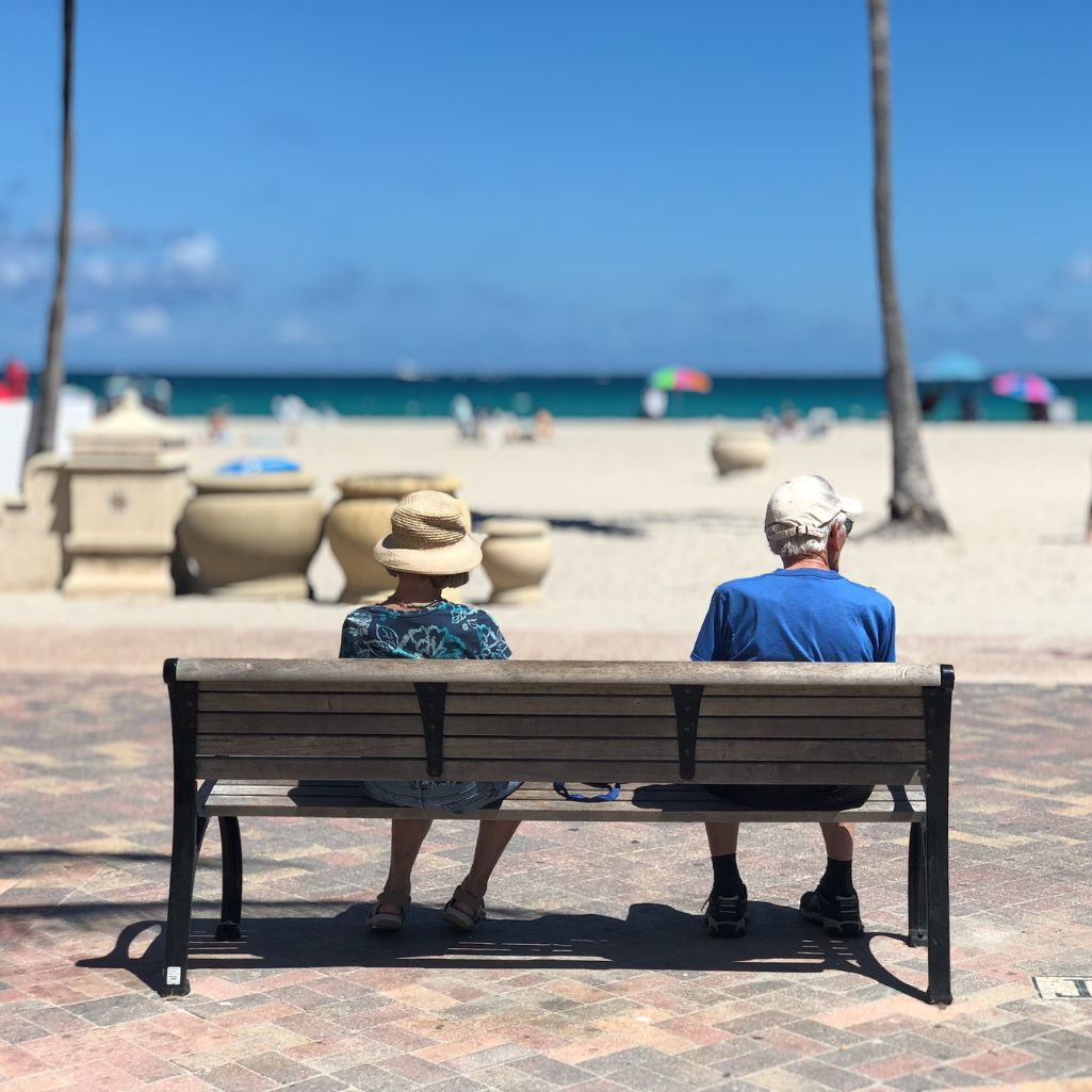Δύο ηλικιωμένοι άνθρωπο κάθονται μακριά ο ένας από τον άλλο σε ένα παγκάκι