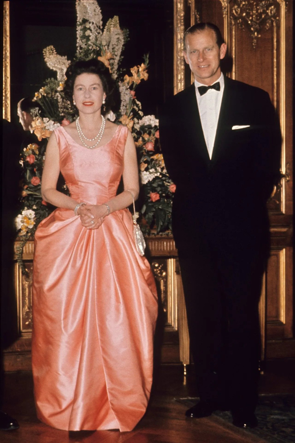 Ιούνιος 1963: Η βασίλισσα φόρεσε ένα κοραλί βραδινό φόρεμα με τις χαρακτηριστικές της πέρλες για να παρευρεθεί σε μια εκδήλωση στο Λονδίνο με τον Δούκα του Εδιμβούργου.
