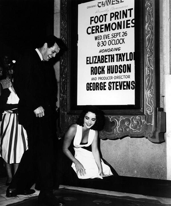 Rock Hudson enters his footprints as Elizabeth Taylor looks on at the premiere of GIANT at Grauman s Chinese Theater 1956