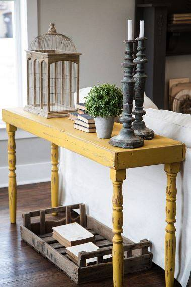 A vintage style yellow table displays decor and adds a pop of color to the living room  as seen on HGTV  s Fixer Upper    Detail