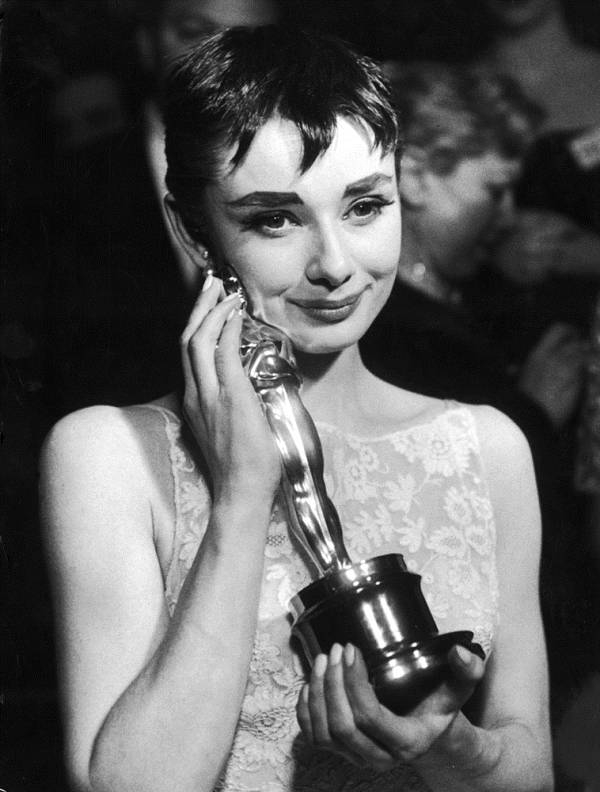 Actress Audrey Hepburn affectionately holding Oscar award she won for her performance in the movie   Roman Holiday   at the Academy Awards ceremony 