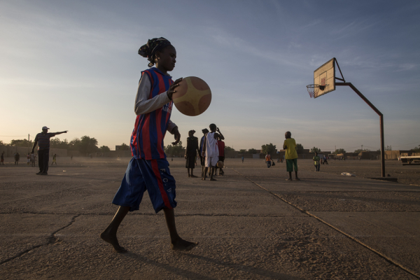 Ένα κορίτσι παίζει μπάσκετ στο ηλιοβασίλεμα σε ένα από τα παλαιότερα εμπορικά κέντρα της Αφρικής.
Κατά τη διάρκεια της τζιχάντ κατοχής το 2012, είχε απαγορευτεί στα κορίτσια να ασχολούνται με τον αθλητισμό και να φορούν σορτς.
Photo: UN Photo/Marco Dor