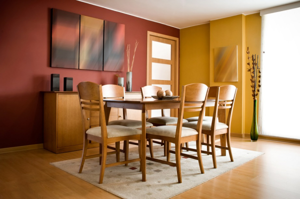 Άλλη μία κλασσική τραπεζαρία σε φυσικό ξύλο. Οι αποχρώσεις του κίτρινου και του μπορντό στους τοίχους συνδυάζονται πολύ αρμονικά με το χρώμα του ξύλου και τα έργα τέχνης.